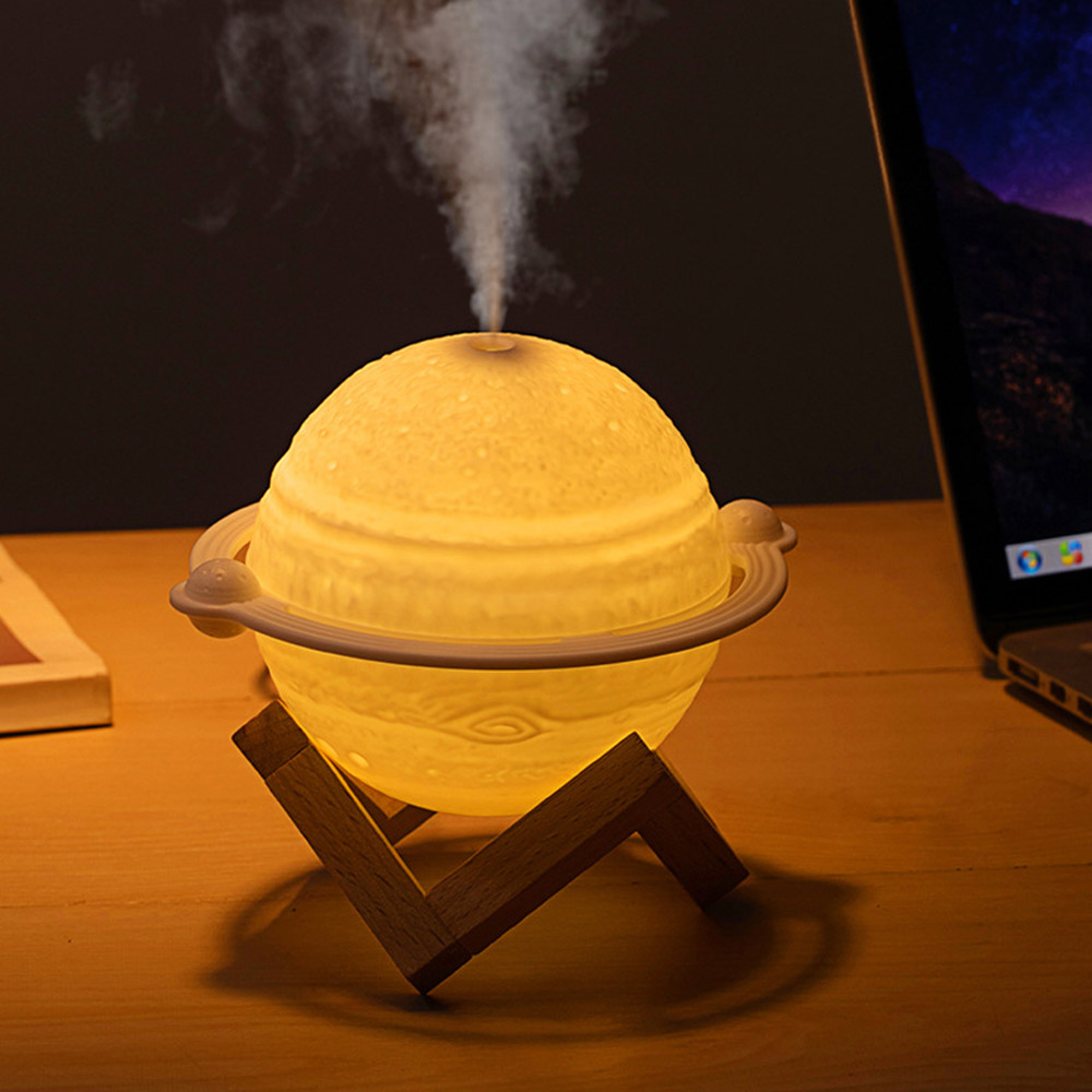 Eine Saturn-förmige Lampe und Luftbefeuchter auf einem Holzständer auf einem Schreibtisch.