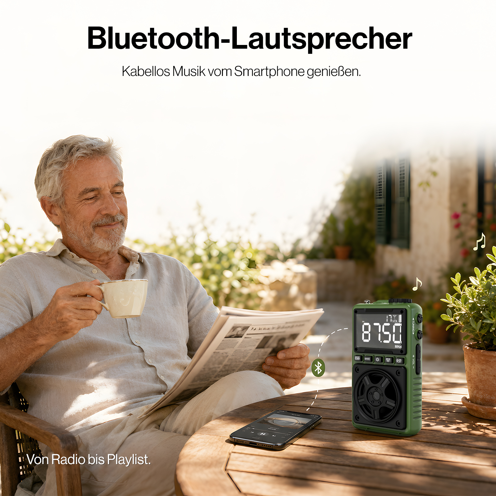 Älterer Mann sitzt auf der Terrasse, liest Zeitung, trinkt Kaffee, daneben Smartphone und ein grünes Radio.