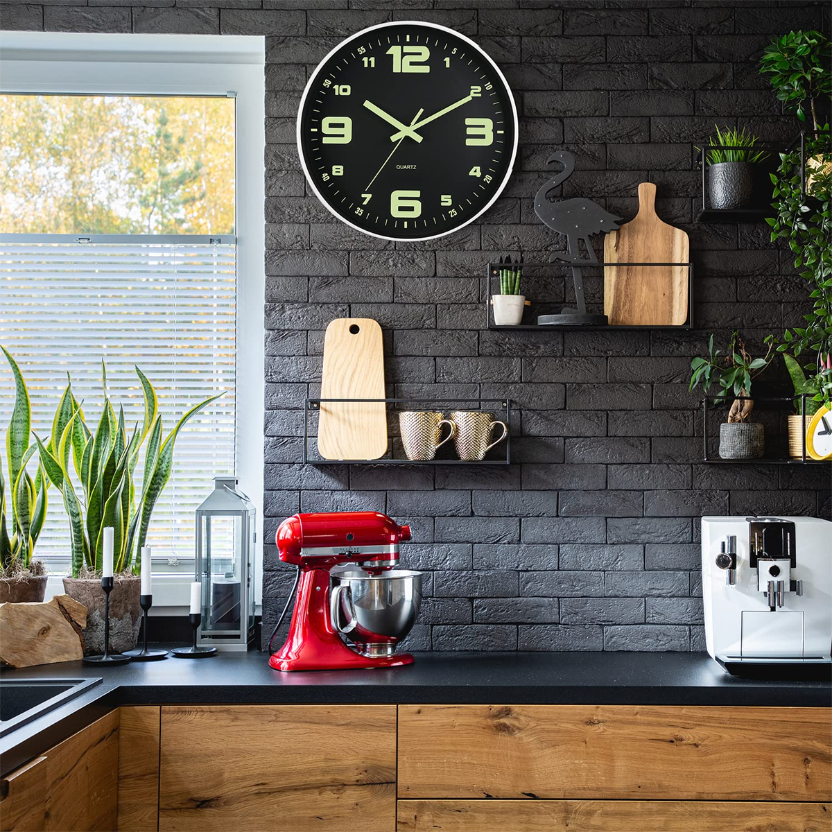 Moderne Küche mit schwarzer Backsteinwand, roter Küchenmaschine, großer Uhr und Pflanzen.