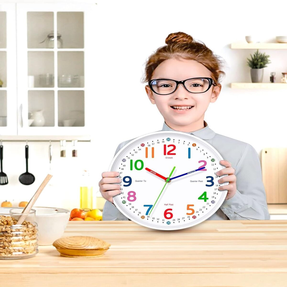 Mädchen mit Brille hält eine bunte Lernwanduhr in der Küche.