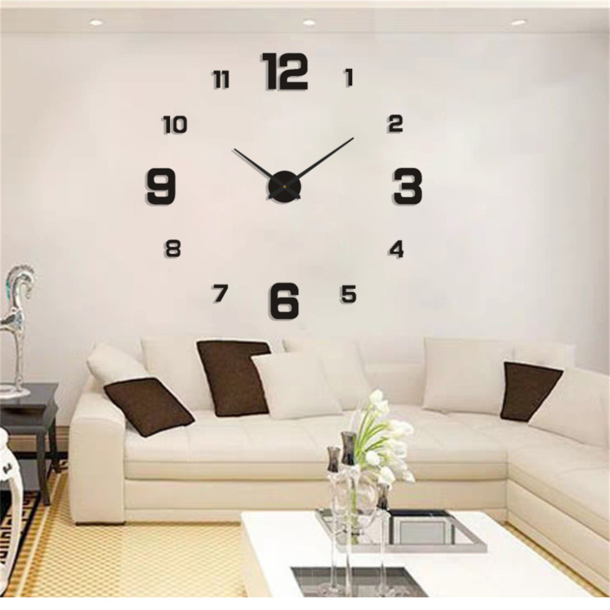 Wohnzimmer mit weißem Ecksofa, Couchtisch und einer großen Wanduhr mit Schwarzen Ziffern.