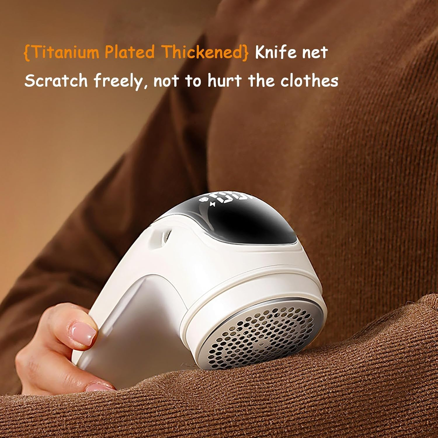 Hand hält einen elektrischen Fusselrasierer auf einem braunen Strickpullover.