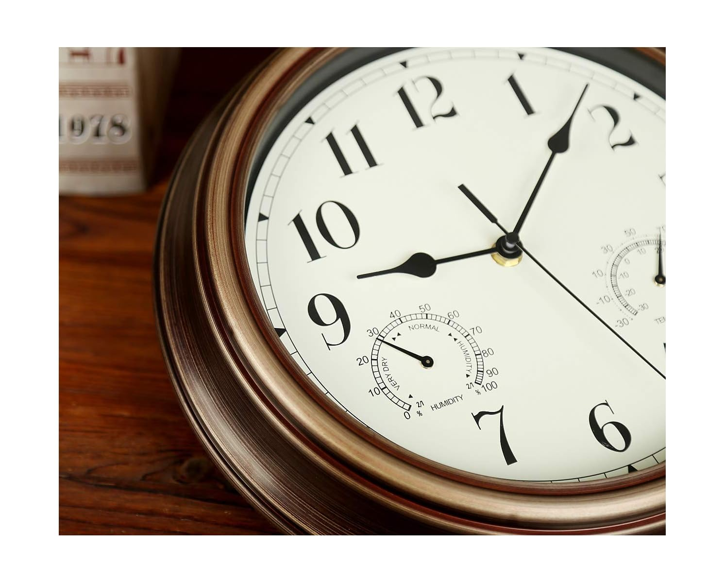 Nahaufnahme einer runden Vintage-Wanduhr mit bronzenem Rahmen, weißem Zifferblatt und kleinen Skalen.