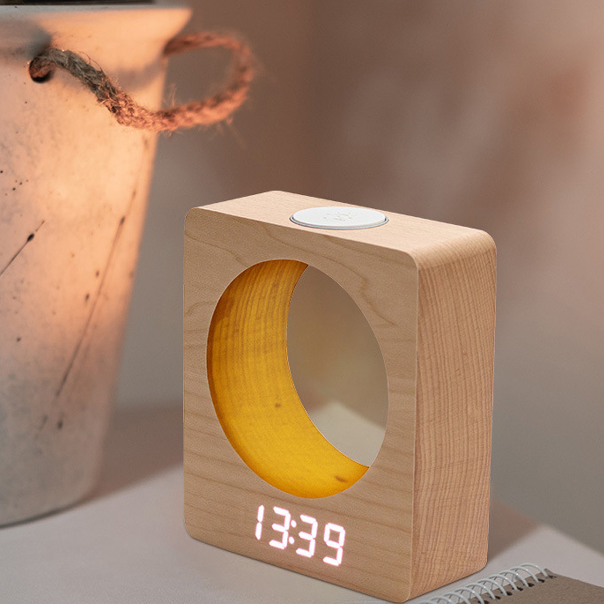Eine rechteckige Digitaluhr aus hellem Holz mit rundem Ausschnitt zeigt 13:39 neben einem Topf.