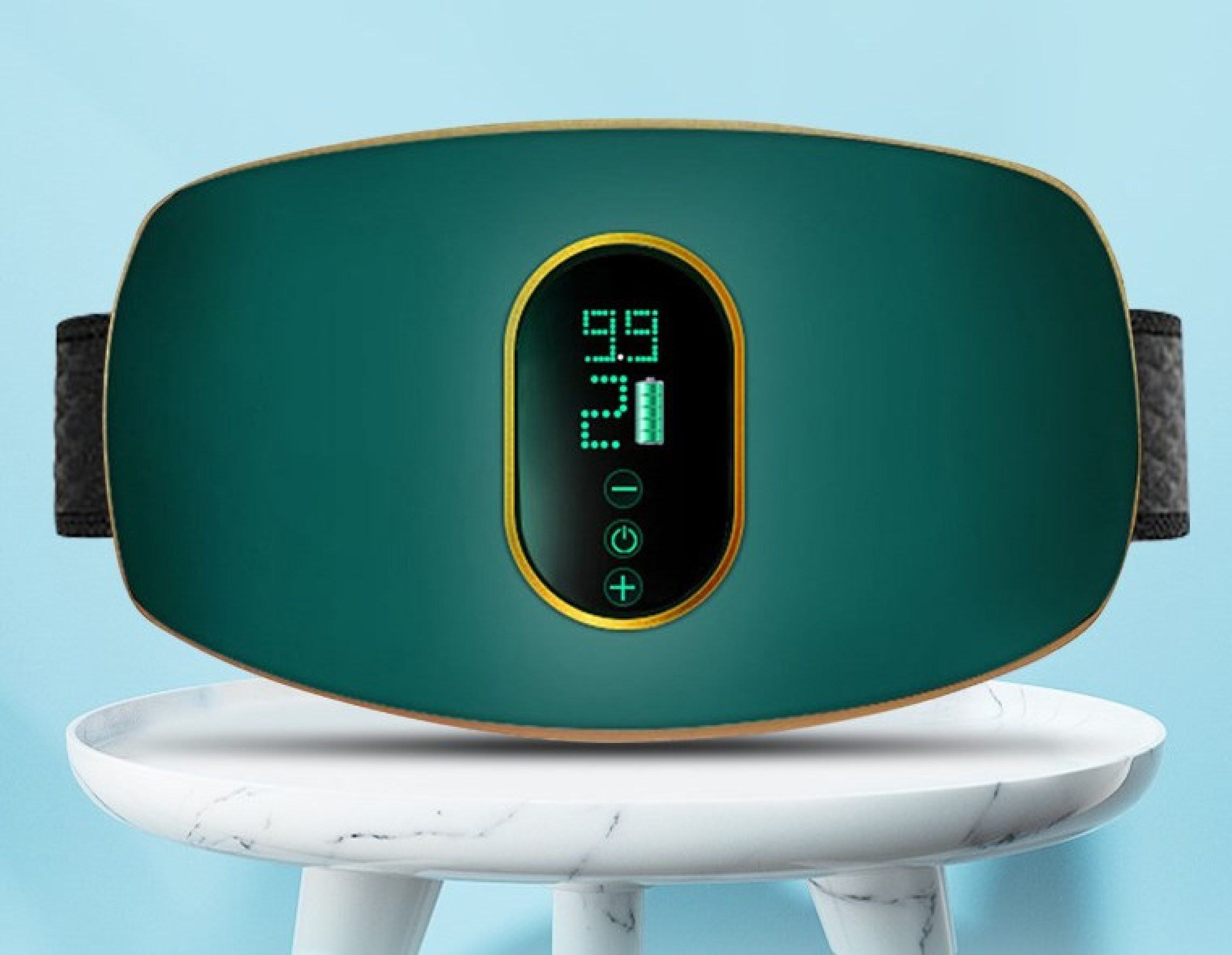 Grüner Massagegürtel mit goldenem Rand und digitalem Display auf einem weißen Tisch vor blauem Hintergrund.