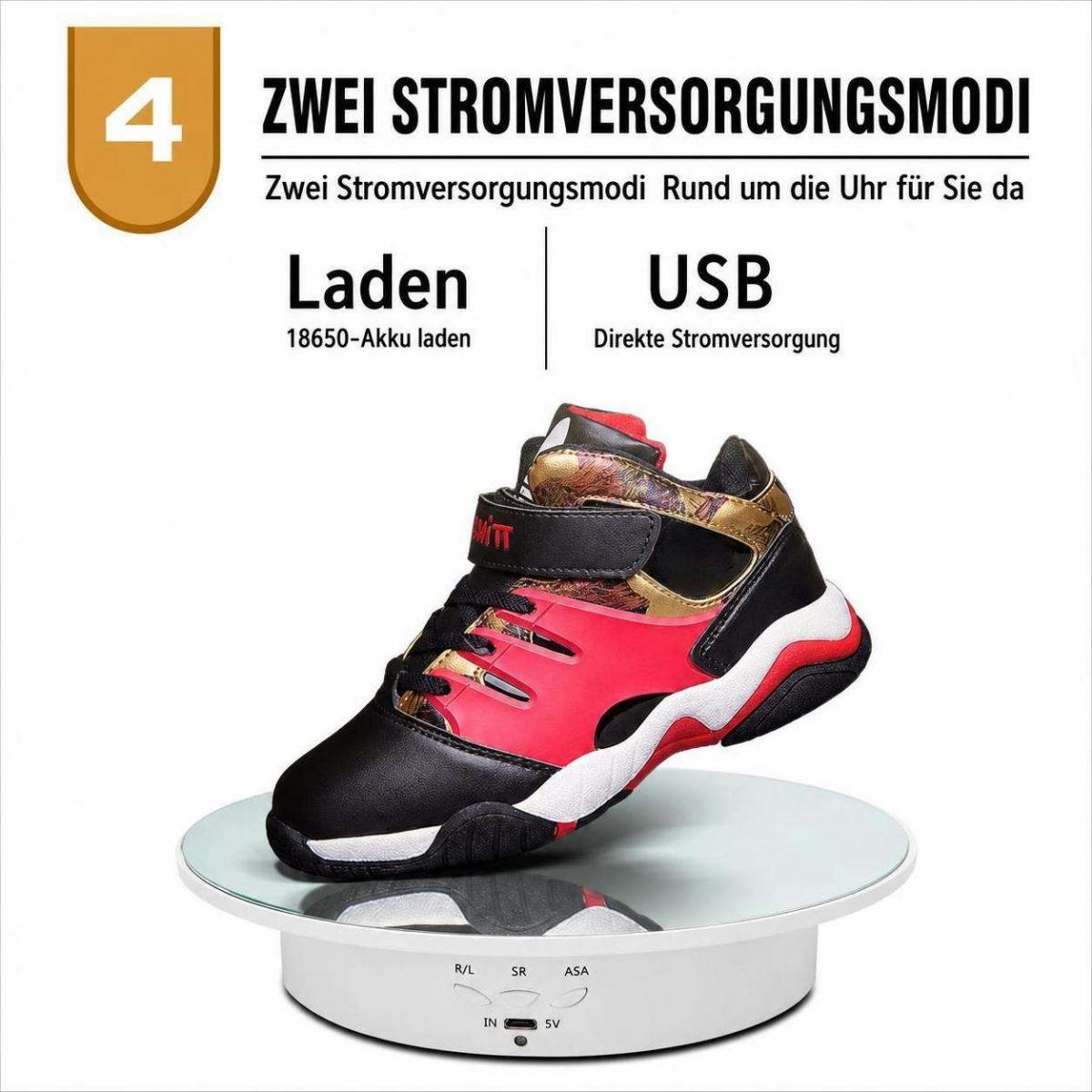 Ein rot-schwarzer Kinderschuh steht auf einer rotierenden weißen Display-Platte mit deutscher Texttafel darüber.