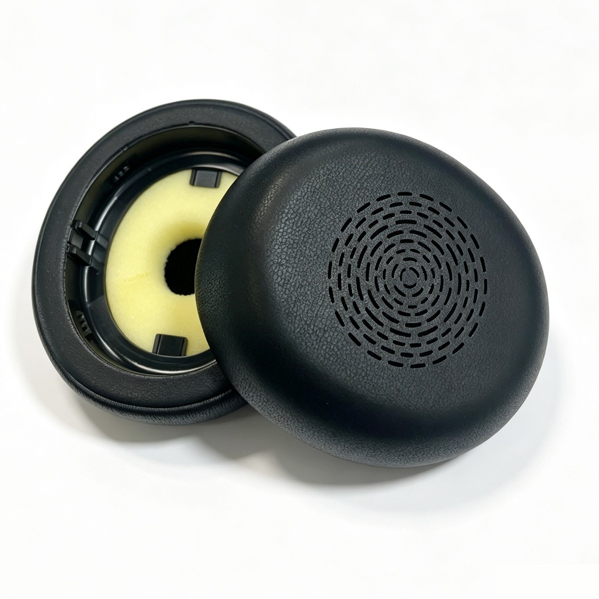 Two black headphone earpads with yellow foam on a white background.