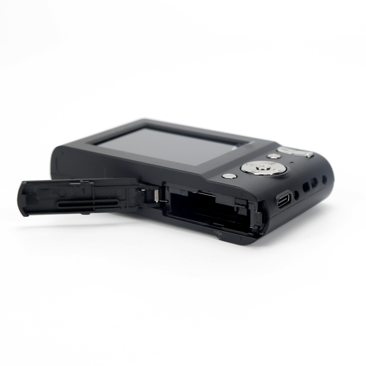 Eine schwarze Digitalkamera mit geöffneter Batteriefachklappe, die das leere Innere zeigt, vor weißem Hintergrund.