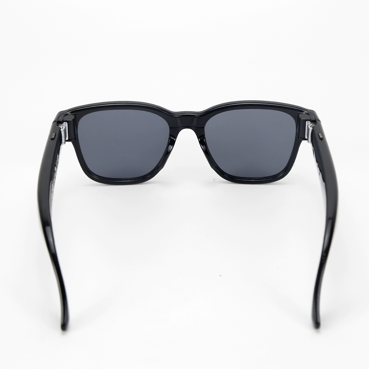 Schwarze Sonnenbrille mit grauen Gläsern von hinten vor weißem Hintergrund fotografiert.