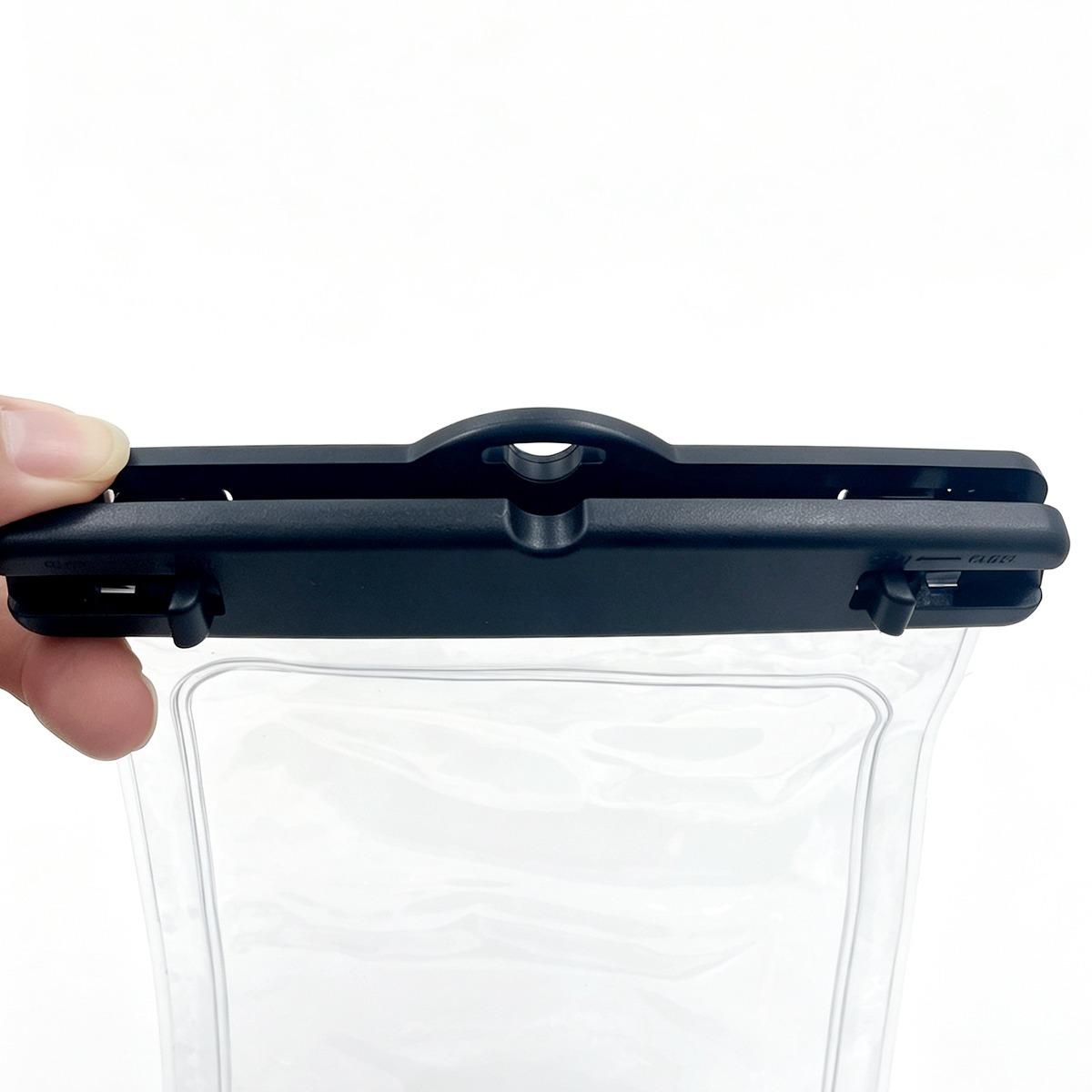 Eine Hand hält den schwarzen Plastikverschluss einer transparenten Schutzhülle vor weißem Hintergrund.