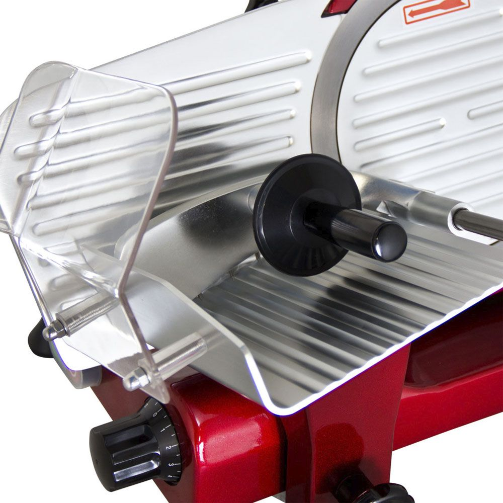 Close-up of a red and silver electric food slicer with a clear plastic guard and black handle.