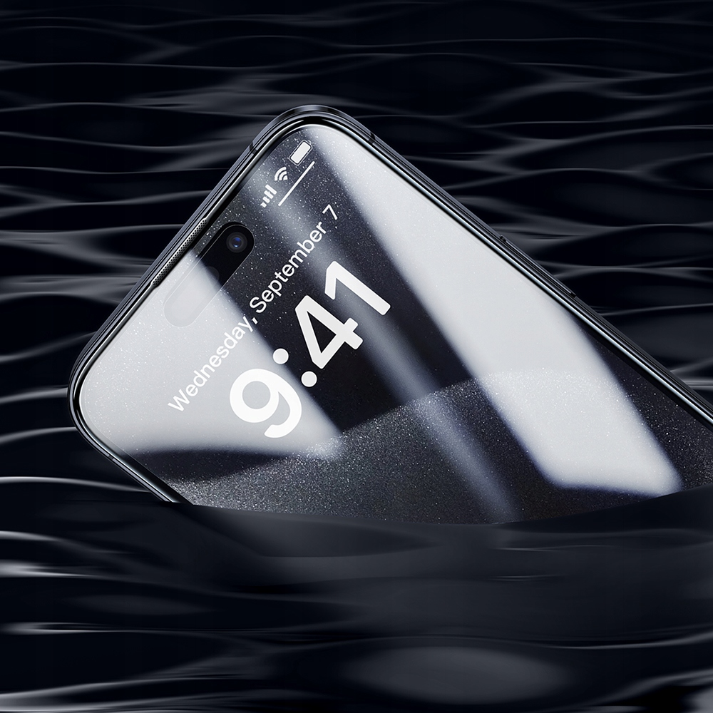 Uno smartphone parzialmente immerso in acqua nera e fluida, che mostra data e ora sullo schermo.