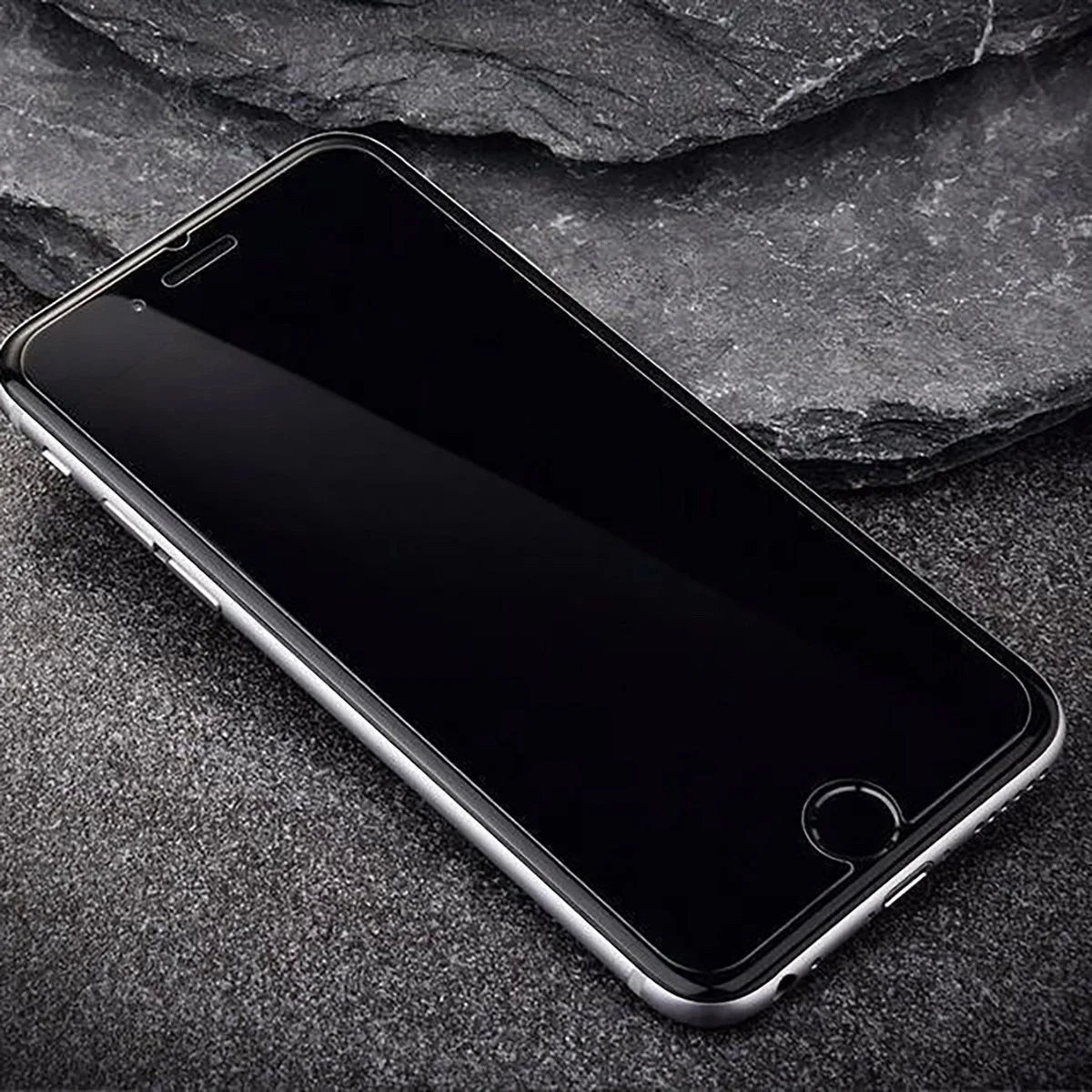 Uno smartphone con schermo nero poggia su una superficie rocciosa scura.
