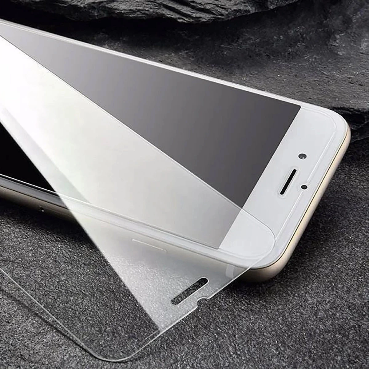 Pellicola protettiva in vetro applicata su uno smartphone su una superficie di pietra scura.