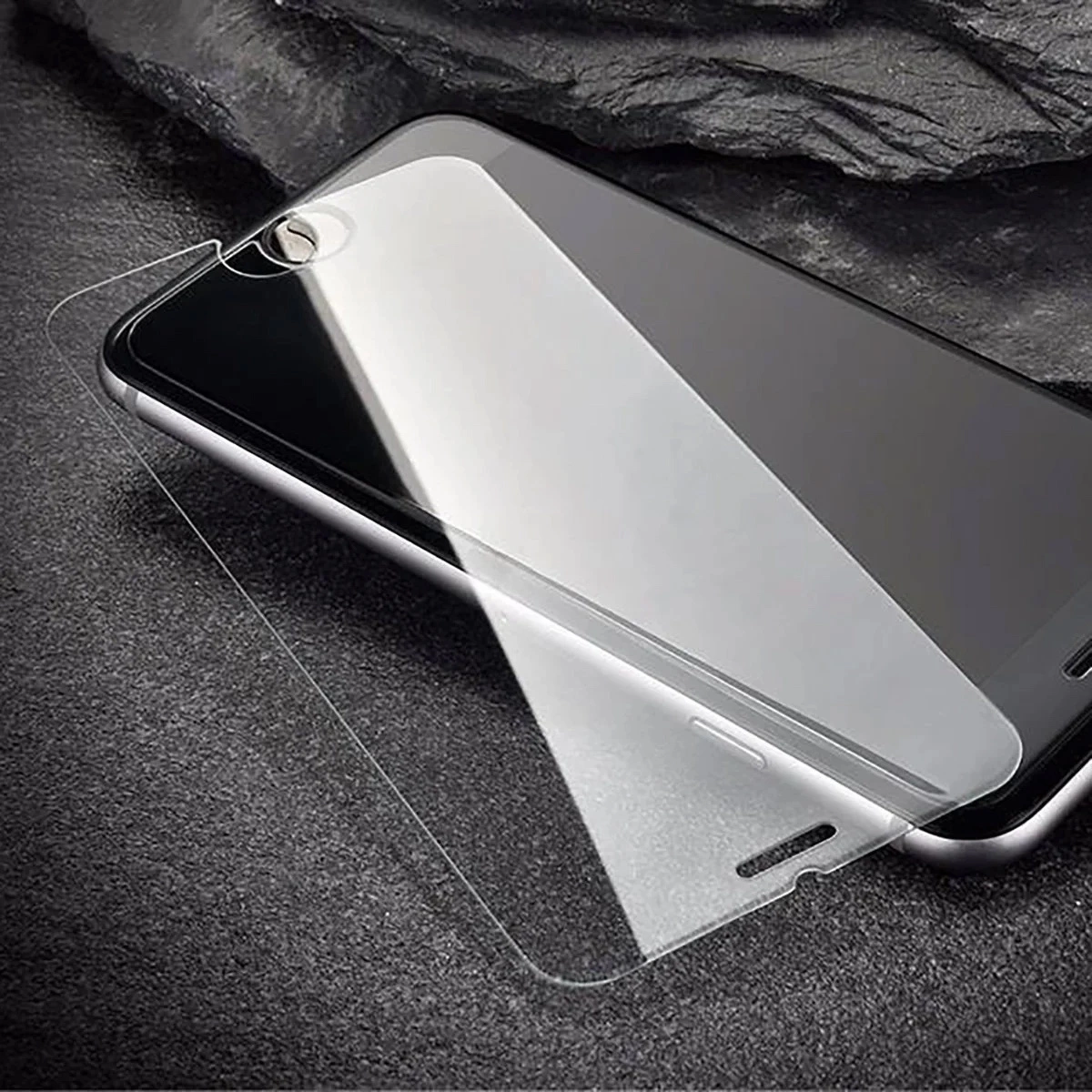 Pellicola protettiva in vetro posizionata su uno smartphone su sfondo scuro.