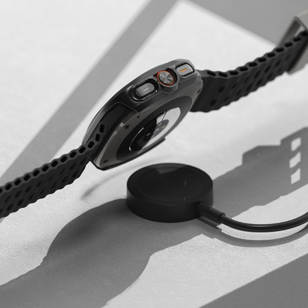 Uno smartwatch nero fluttua sopra una base di ricarica wireless circolare su una superficie chiara.