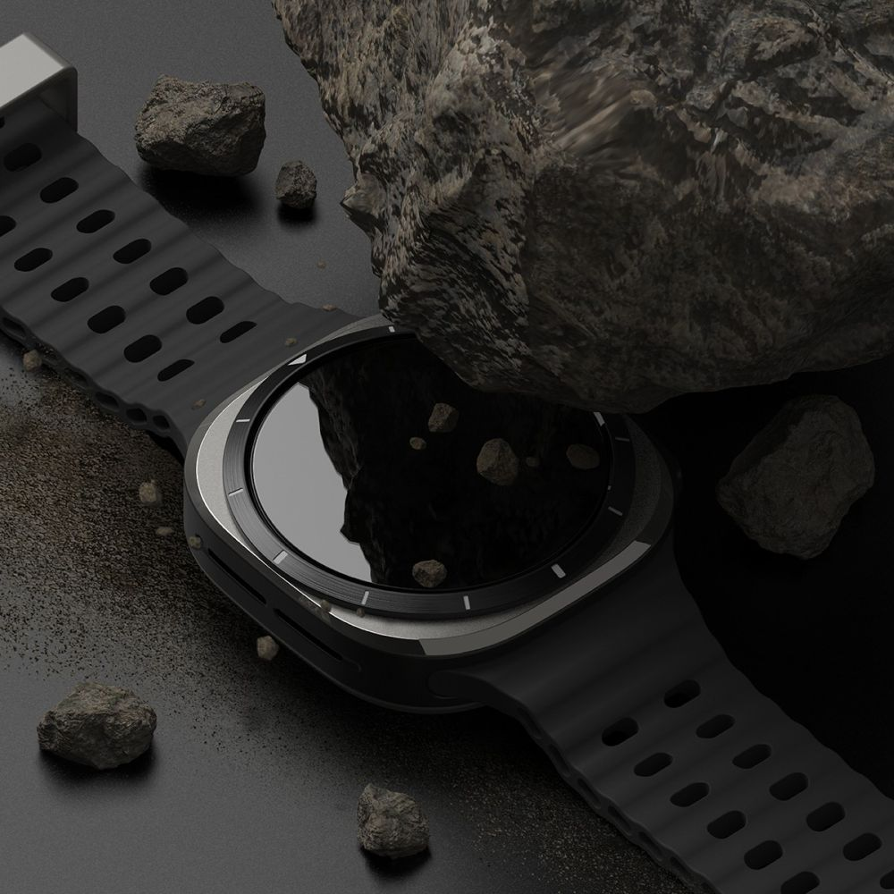 Un orologio sportivo nero con cinturino in gomma giace su una superficie scura, circondato da pietre.