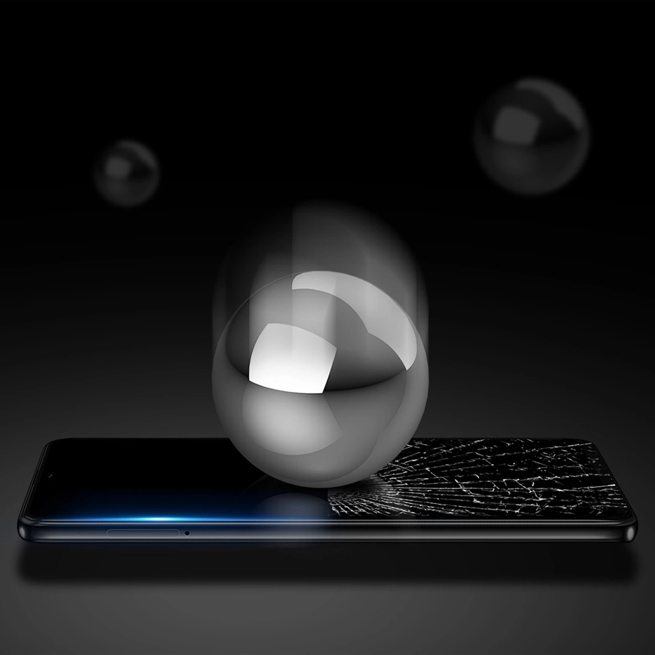 Una sfera metallica argentata cade sullo schermo rotto di uno smartphone su sfondo scuro.