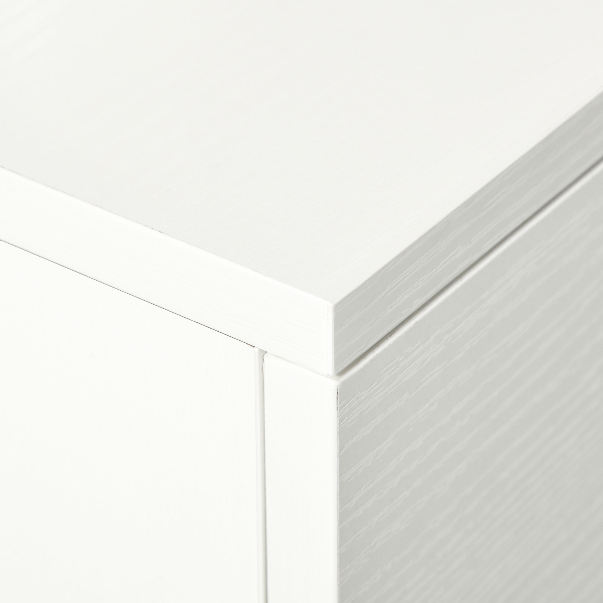 Primer plano de la esquina de una caja de madera blanca con veta visible.