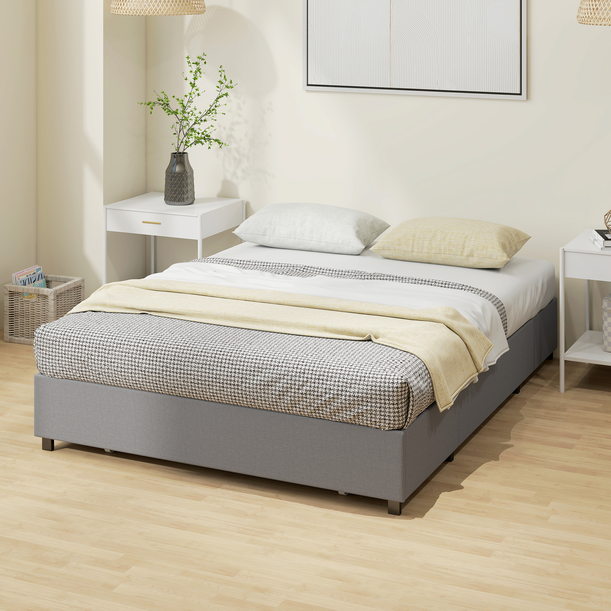 Una cama tapizada en gris con ropa de cama estampada en un dormitorio luminoso, flanqueada por mesitas.