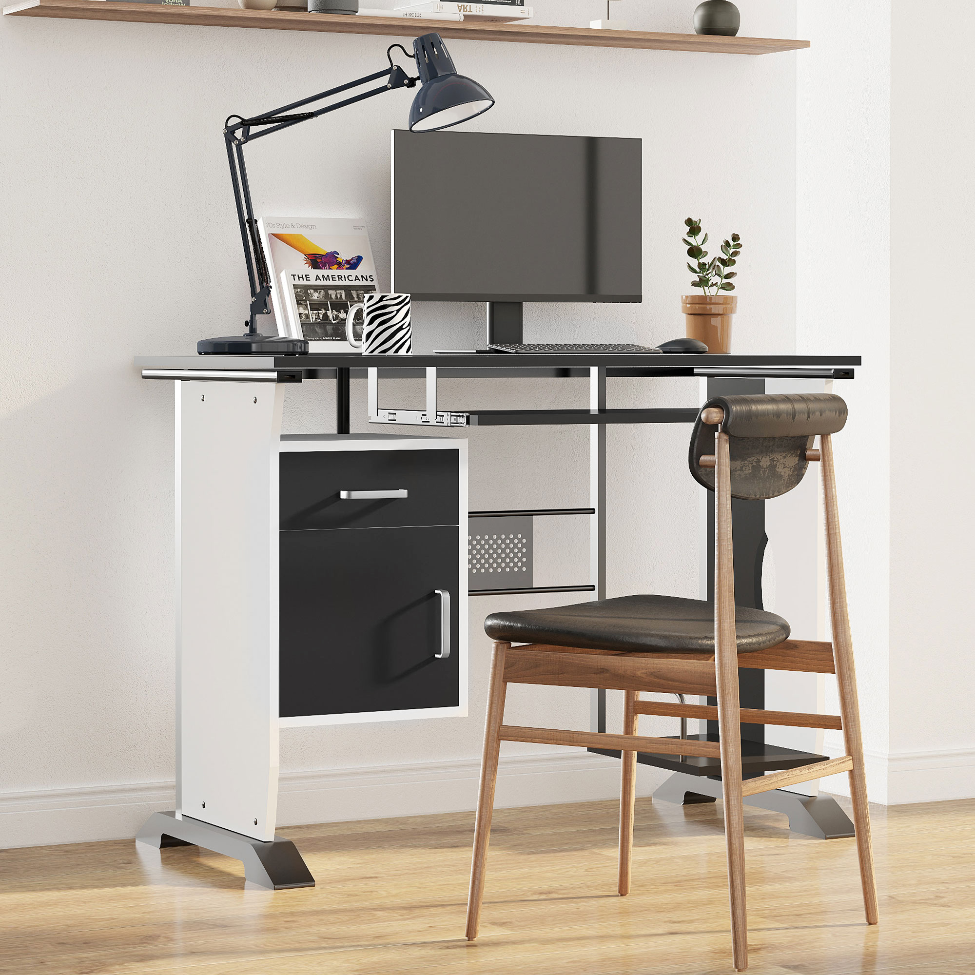 Scrivania moderna con computer, lampada e sedia in una stanza luminosa.