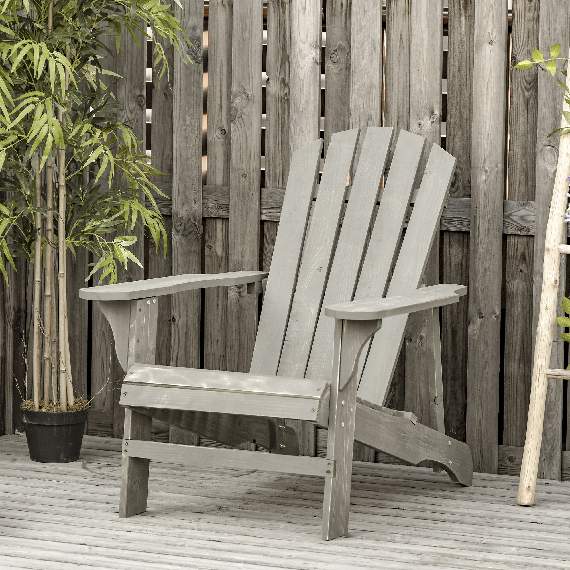 Una silla de patio de madera gris sobre una terraza de madera frente a una cerca con plantas.