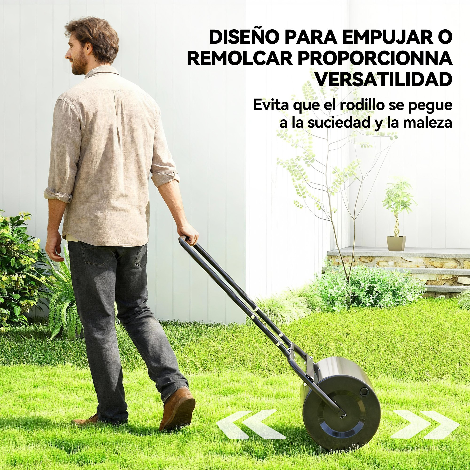 Un hombre con camisa beige arrastra un rodillo de jardín negro por el césped.
