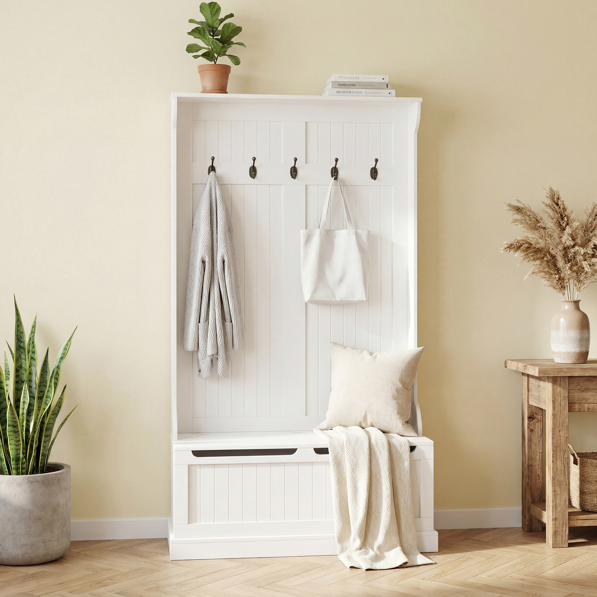 Un mueble recibidor blanco con ganchos, chaqueta, bolso y cojín, flanqueado por plantas.