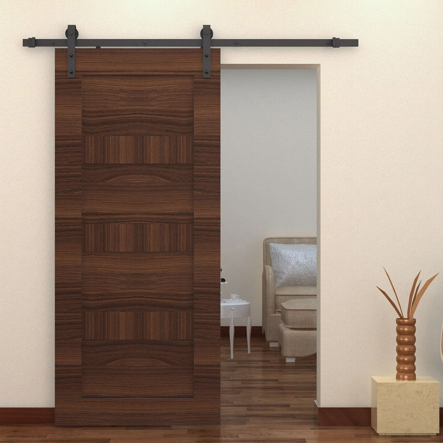 Una puerta corredera de madera en un riel metálico que abre parcialmente una habitación con muebles.