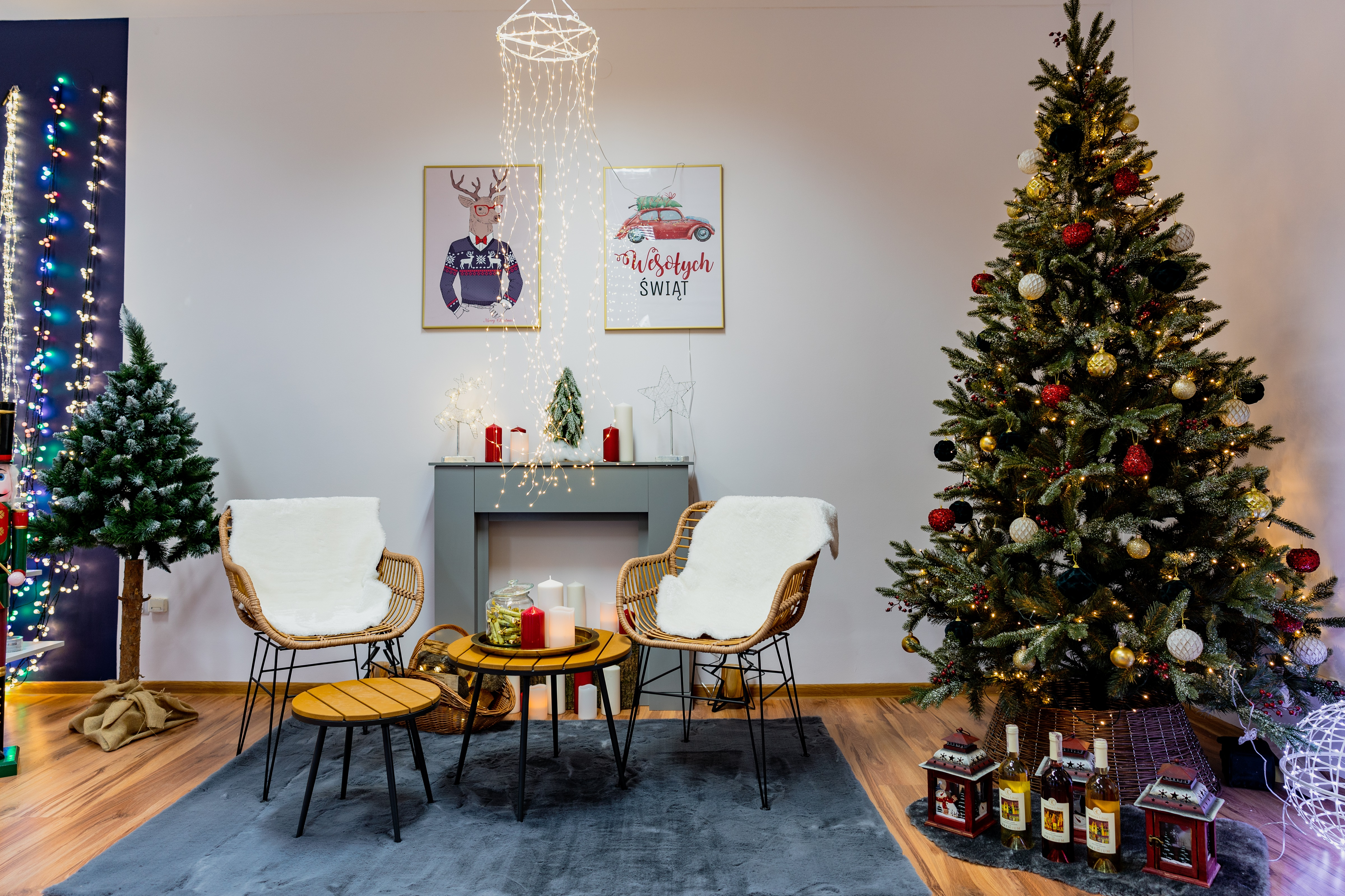 Przytulny salon z choinką, dwoma wiklinowymi fotelami, kominkiem i świątecznym wystrojem.