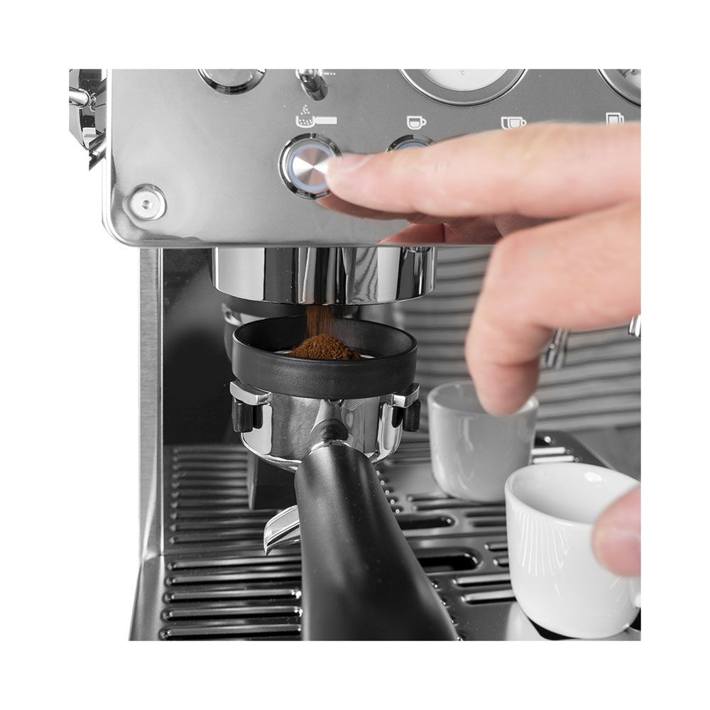 Un doigt appuie sur un bouton de la cafetière tandis que le café moulu tombe dans le porte-filtre.