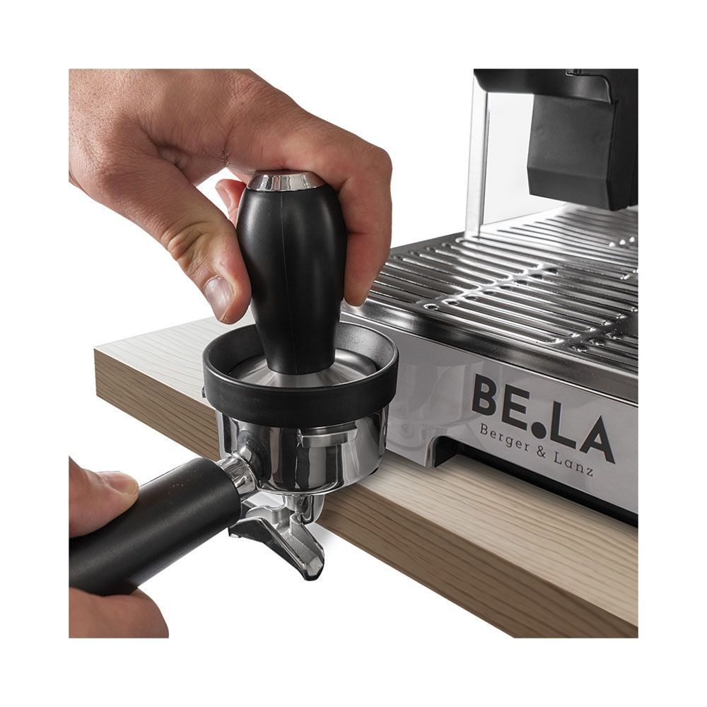 Une main utilise un tamper pour tasser le café dans le porte-filtre.