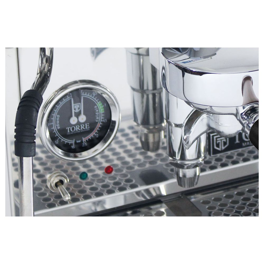 Gros plan d'une machine à espresso chromée avec manomètre noir TORRE, interrupteur à bascule et voyants lumineux.