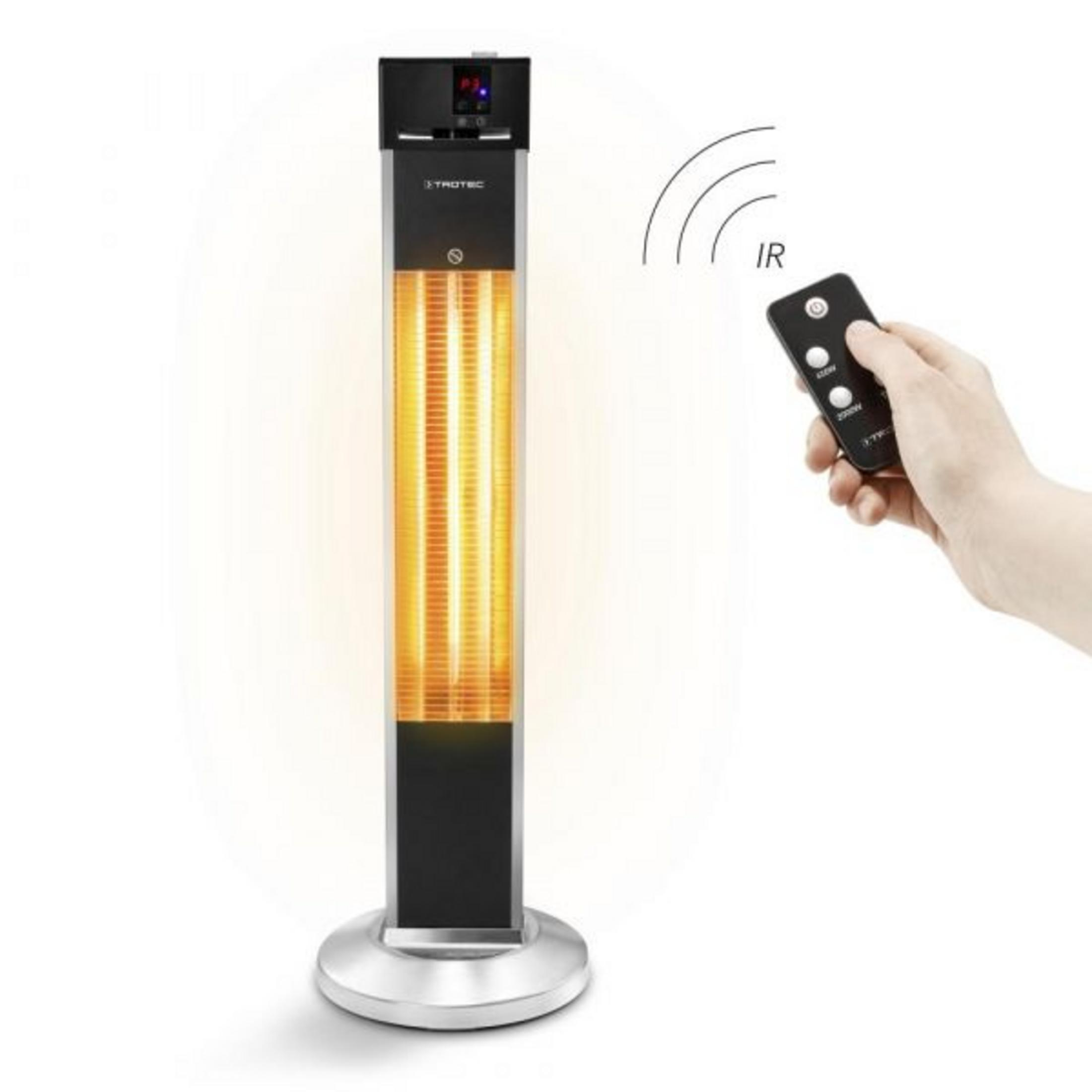 Una stufa a infrarossi a piantana con elemento luminoso è azionata da una mano con telecomando.