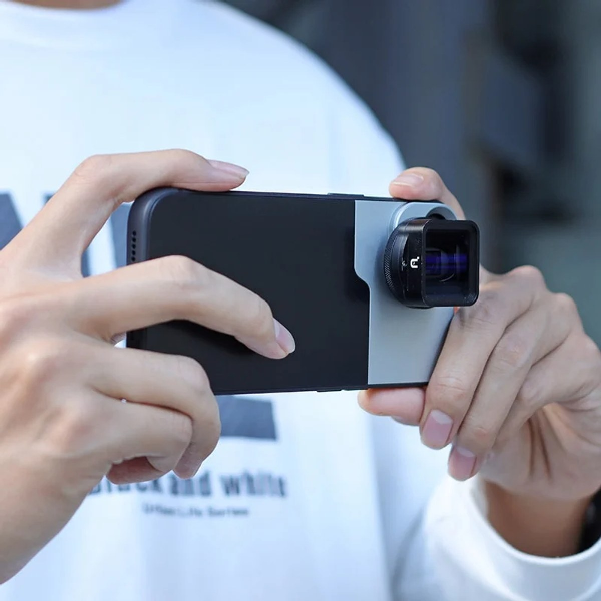 Person hält ein Smartphone mit einer aufgesetzten quadratischen Kamera-Linse.