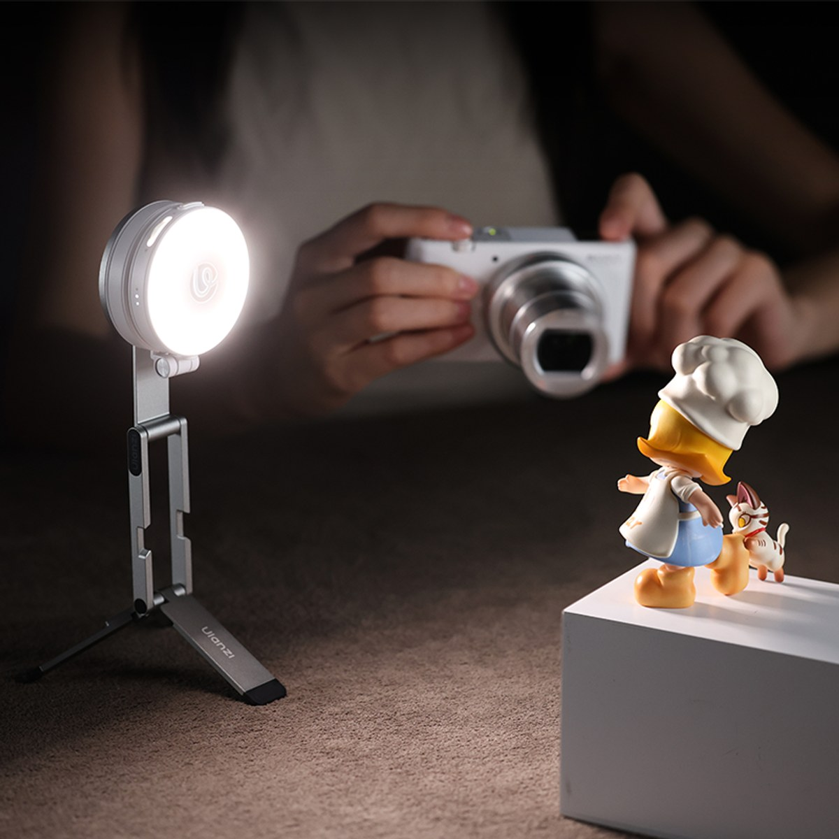 Iemand houdt een camera vast terwijl een heldere lamp een klein koksbeeldje verlicht.