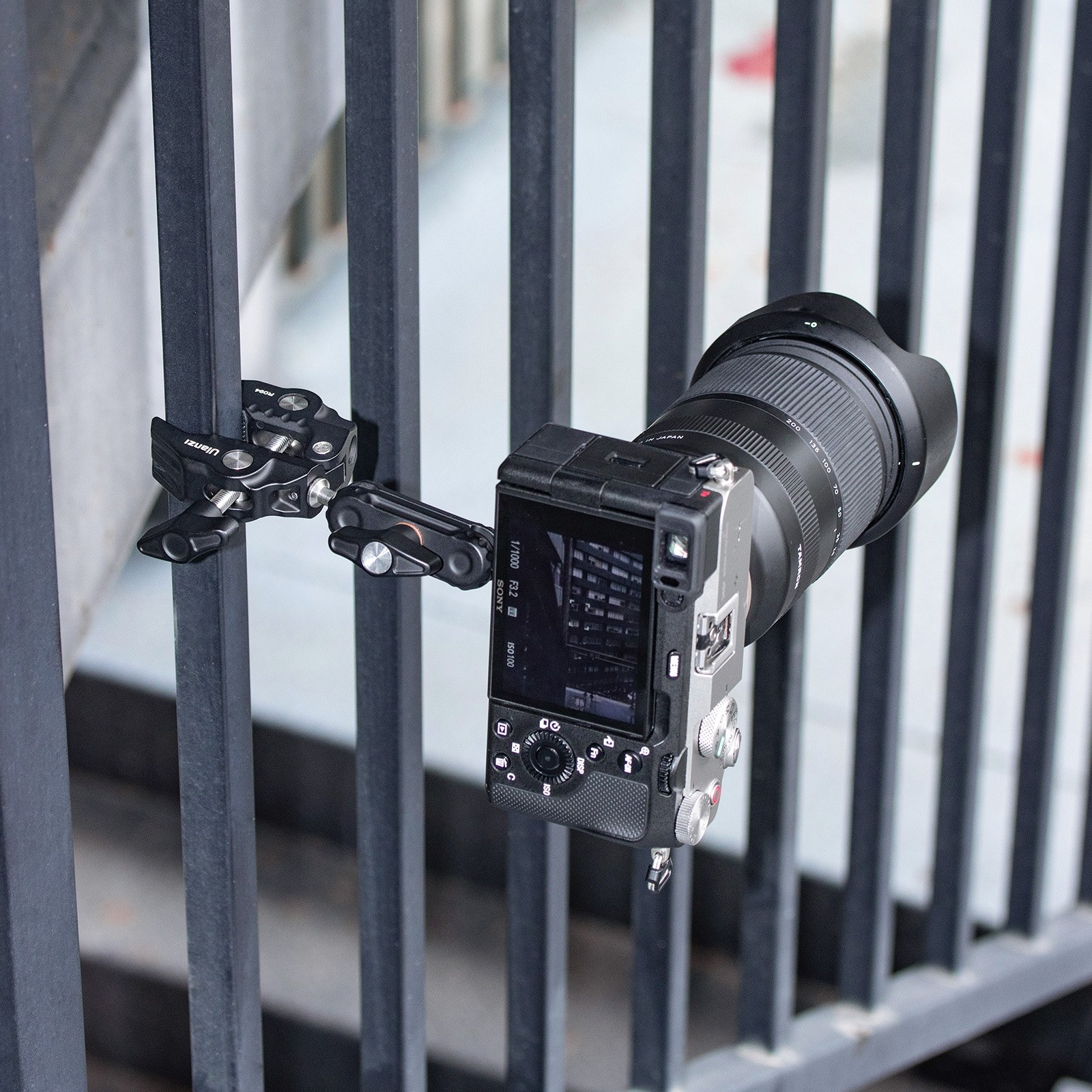 Una telecamera nera attaccata a una ringhiera metallica tramite un morsetto.