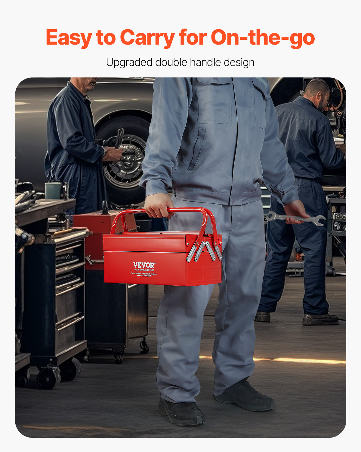 Un mecánico con ropa de trabajo gris lleva una caja de herramientas roja de VEVOR en un taller.