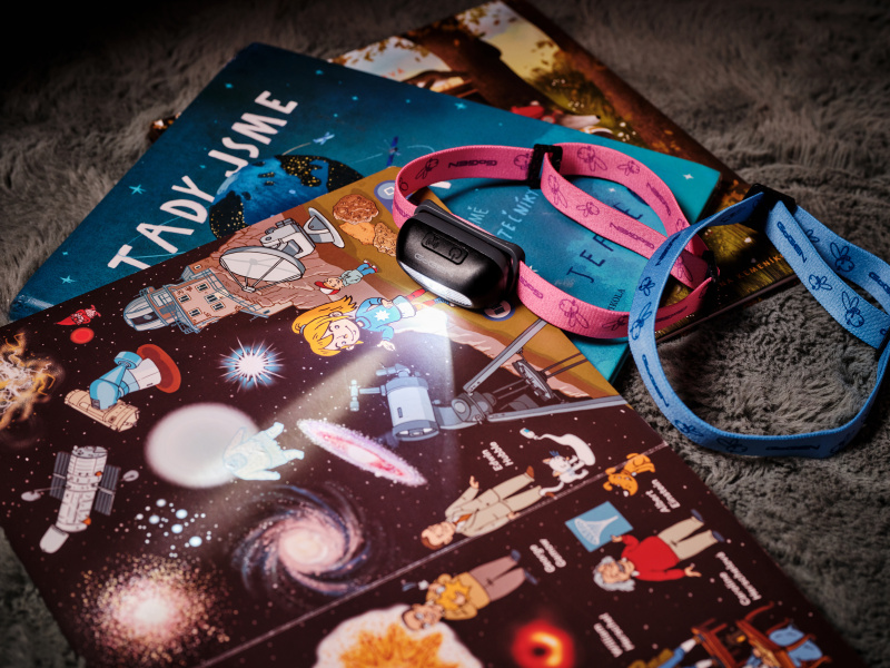 Eine schwarze Stirnlampe liegt auf einem Buch zum Thema Weltraum, umgeben von Kinderbüchern.