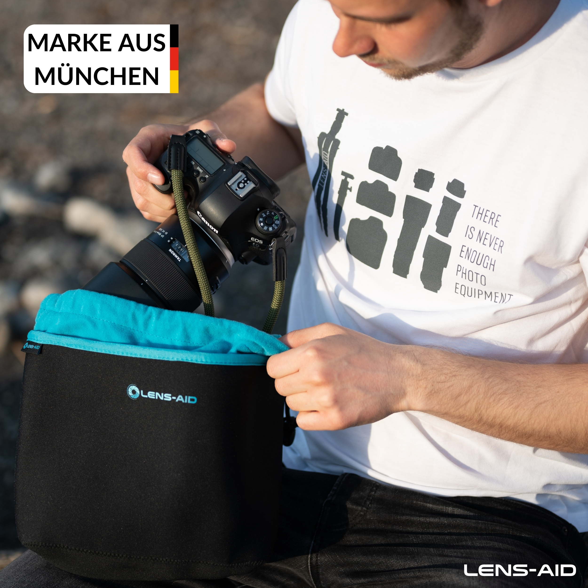 Ein Mann zieht eine schwarze Kamera mit grünem Gurt aus einer schwarz-blauen Lens-Aid-Tasche.