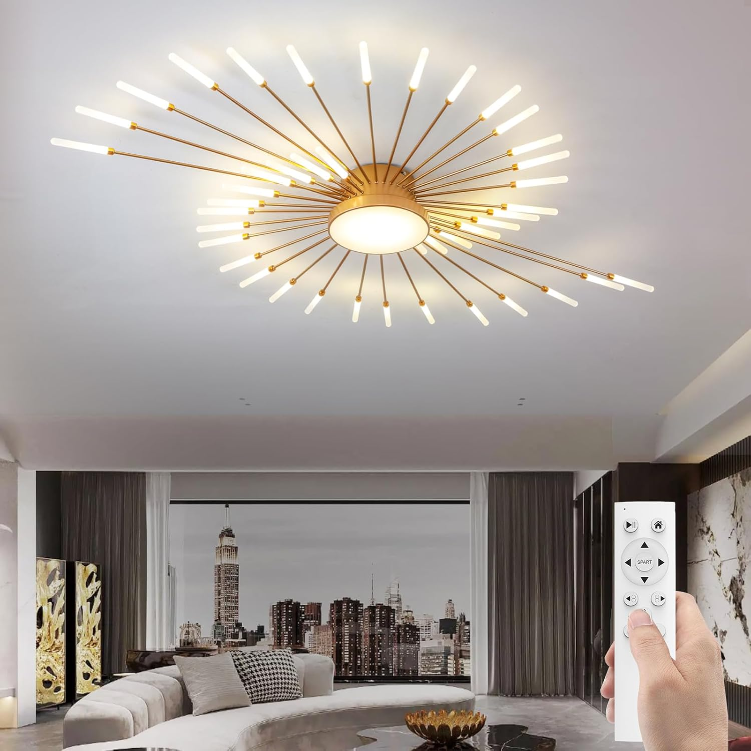 Eine moderne goldene Deckenleuchte mit strahlenden Armen an einer weißen Decke, darunter eine Hand mit Fernbedienung.