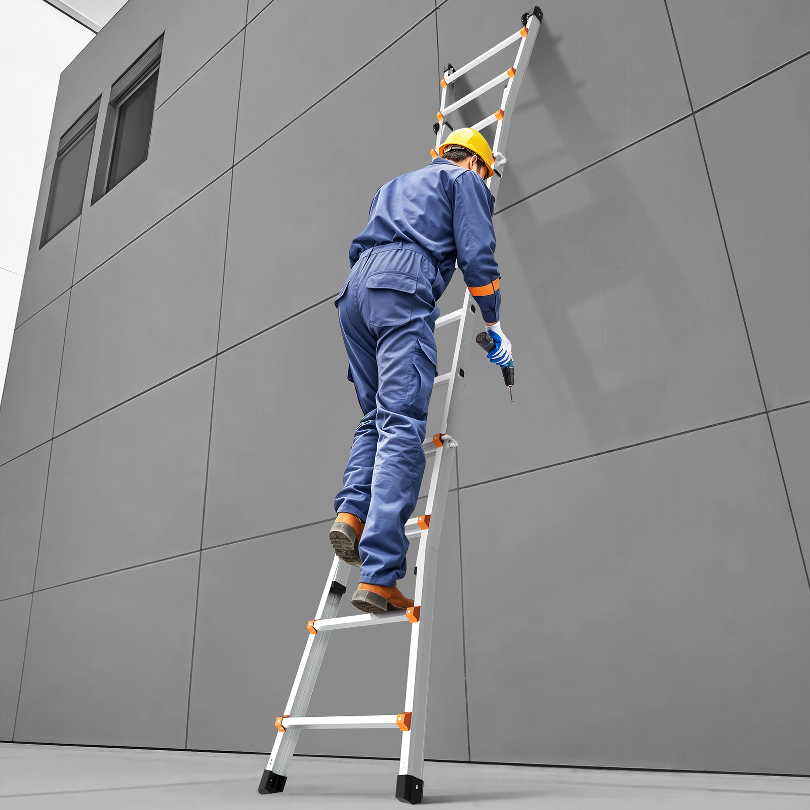 Un trabajador con mameluco azul y casco amarillo sube una escalera contra una pared gris, sosteniendo un taladro.