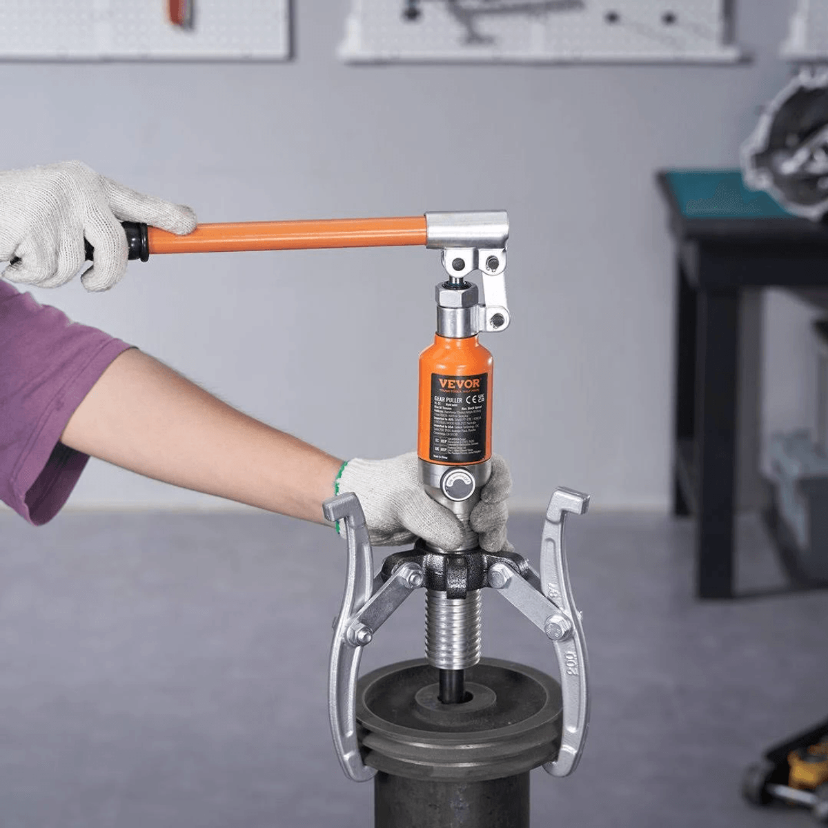 Persona operando un extractor hidráulico naranja y plateado en una pieza de maquinaria.
