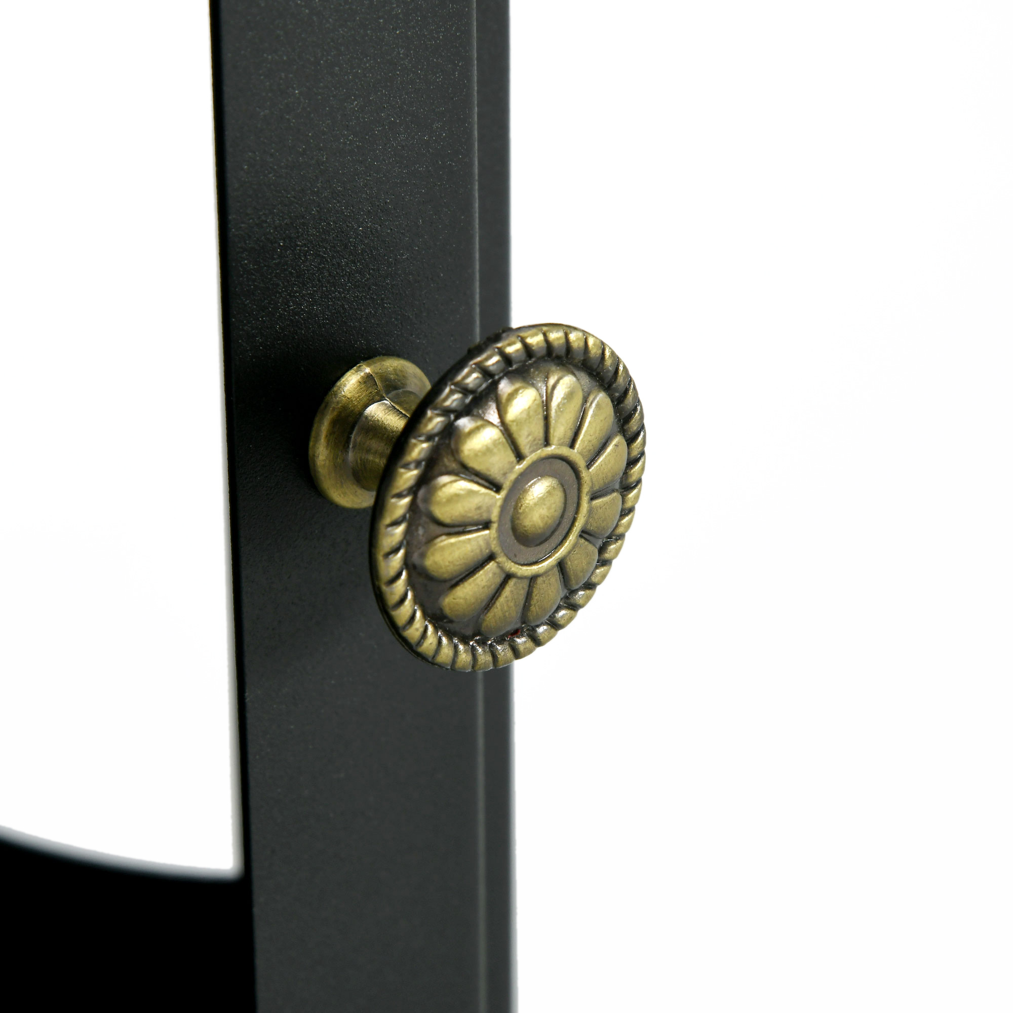 Un pomo de mueble decorativo, redondo y de color latón con un patrón floral en un pilar de metal negro.