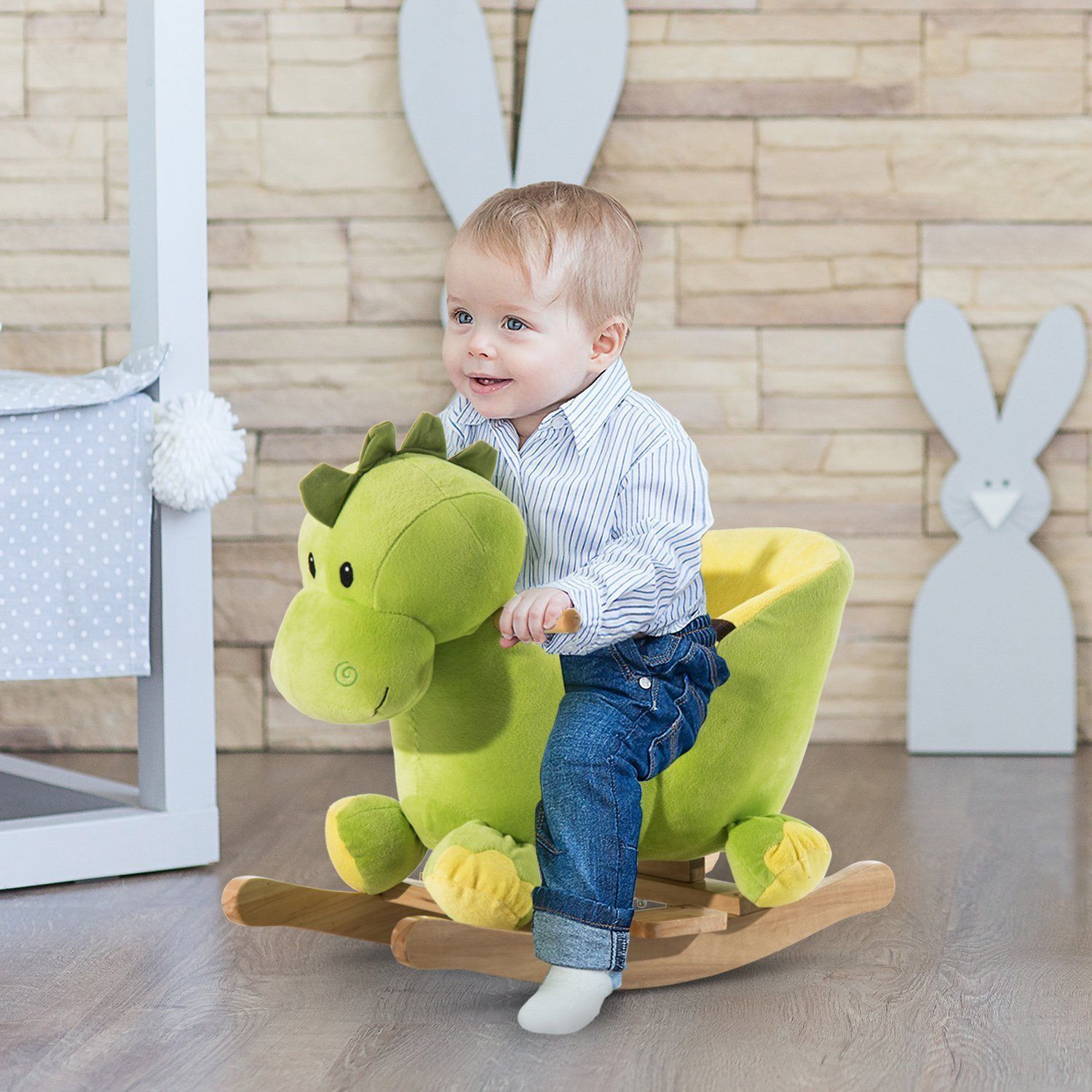 Un niño pequeño sonríe mientras monta un dinosaurio mecedor de peluche verde en una guardería.