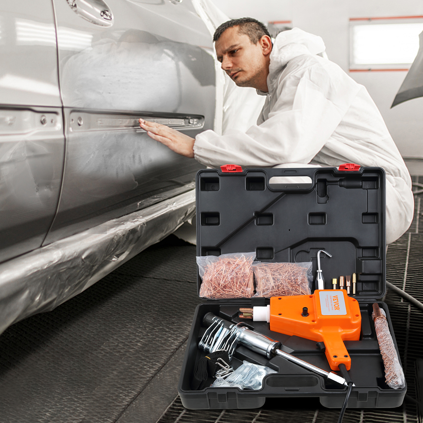 Un mecánico con mameluco blanco inspecciona un auto plateado mientras un kit sacabollos está enfrente.