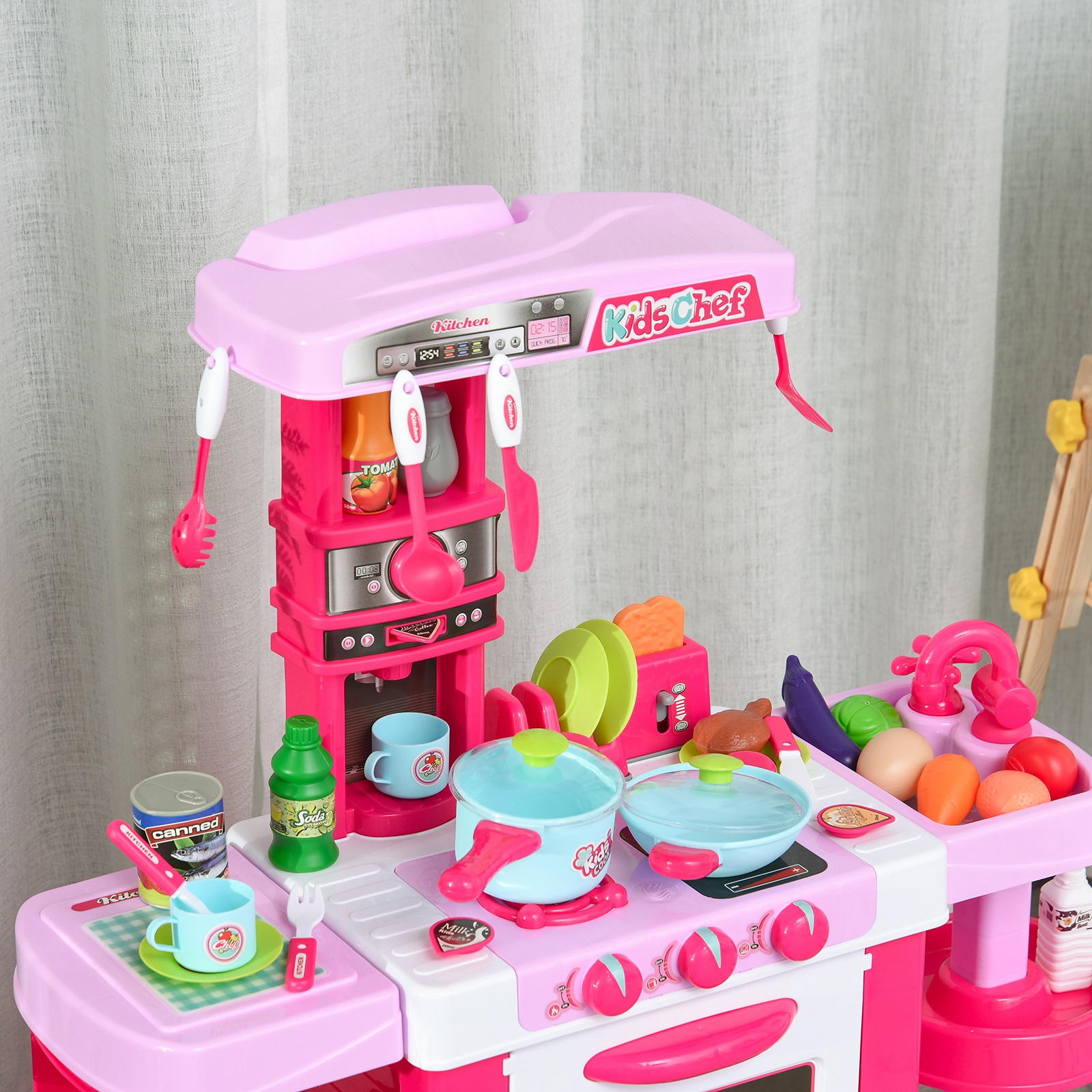Una cocina de juguete para niños de color rosa con accesorios, ollas y comida frente a una cortina.