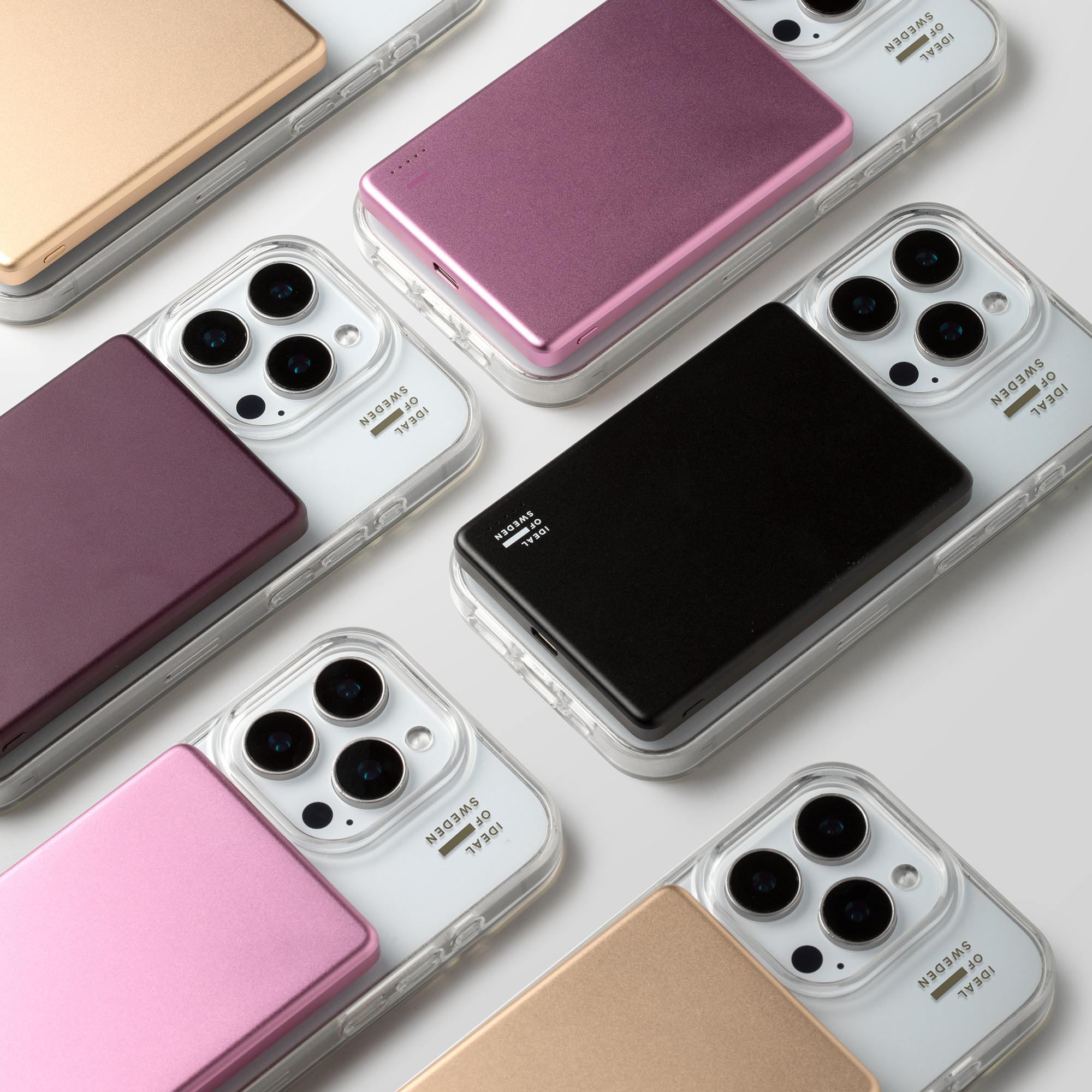 Quatre smartphones dans des coques transparentes avec des batteries externes sur fond clair.