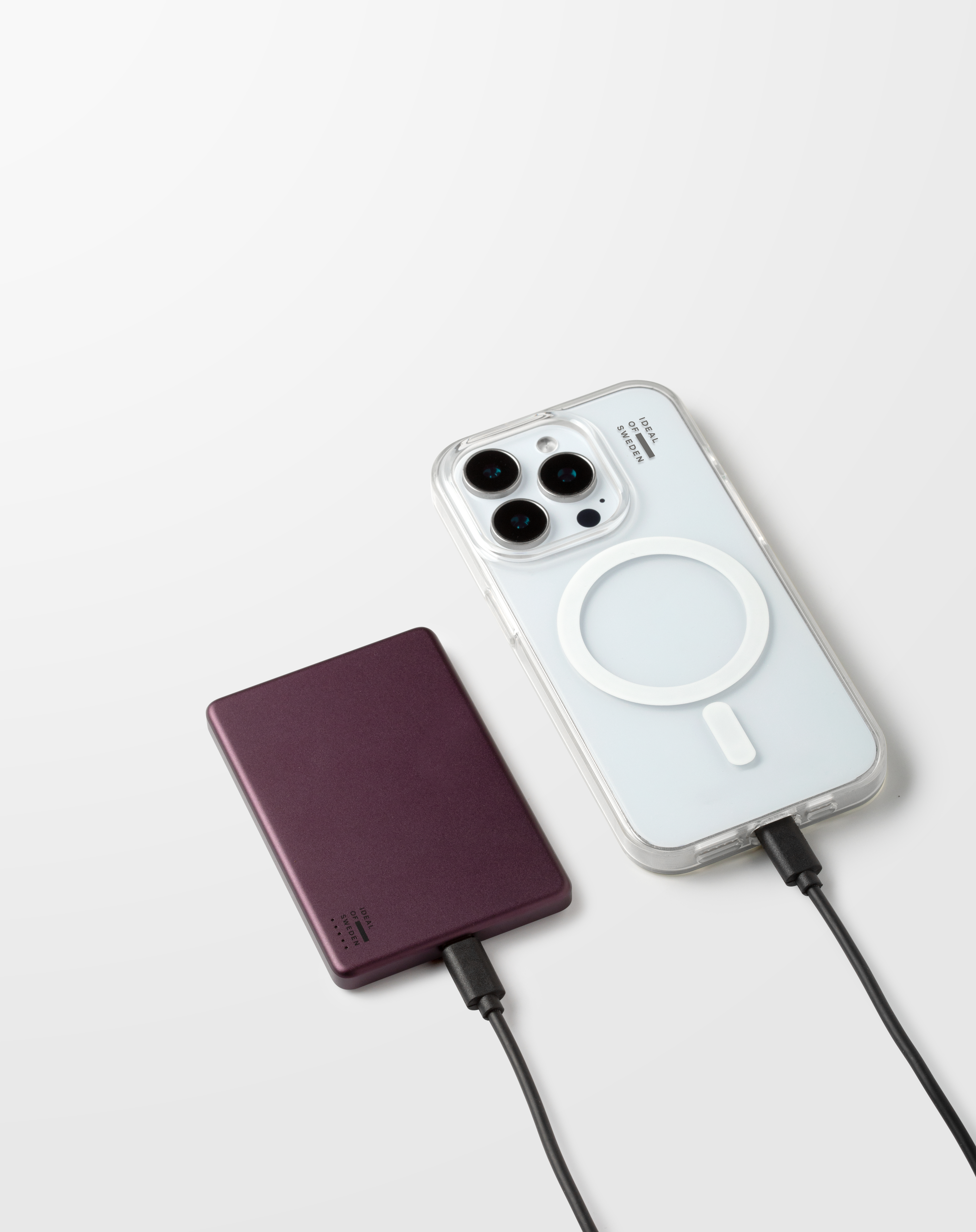 Un smartphone et une batterie externe reposent sur un fond blanc, reliés par des câbles noirs.