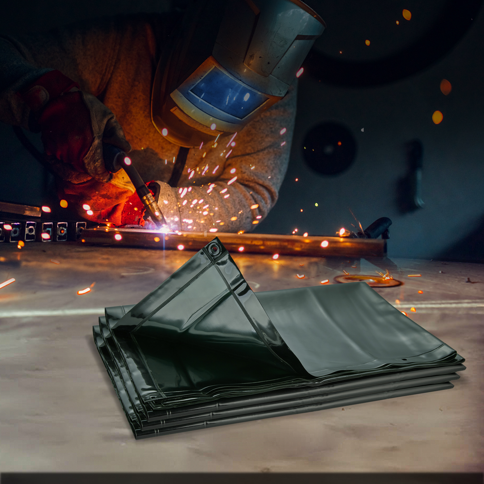 Una lona negra doblada en primer plano, mientras un trabajador suelda metal al fondo.